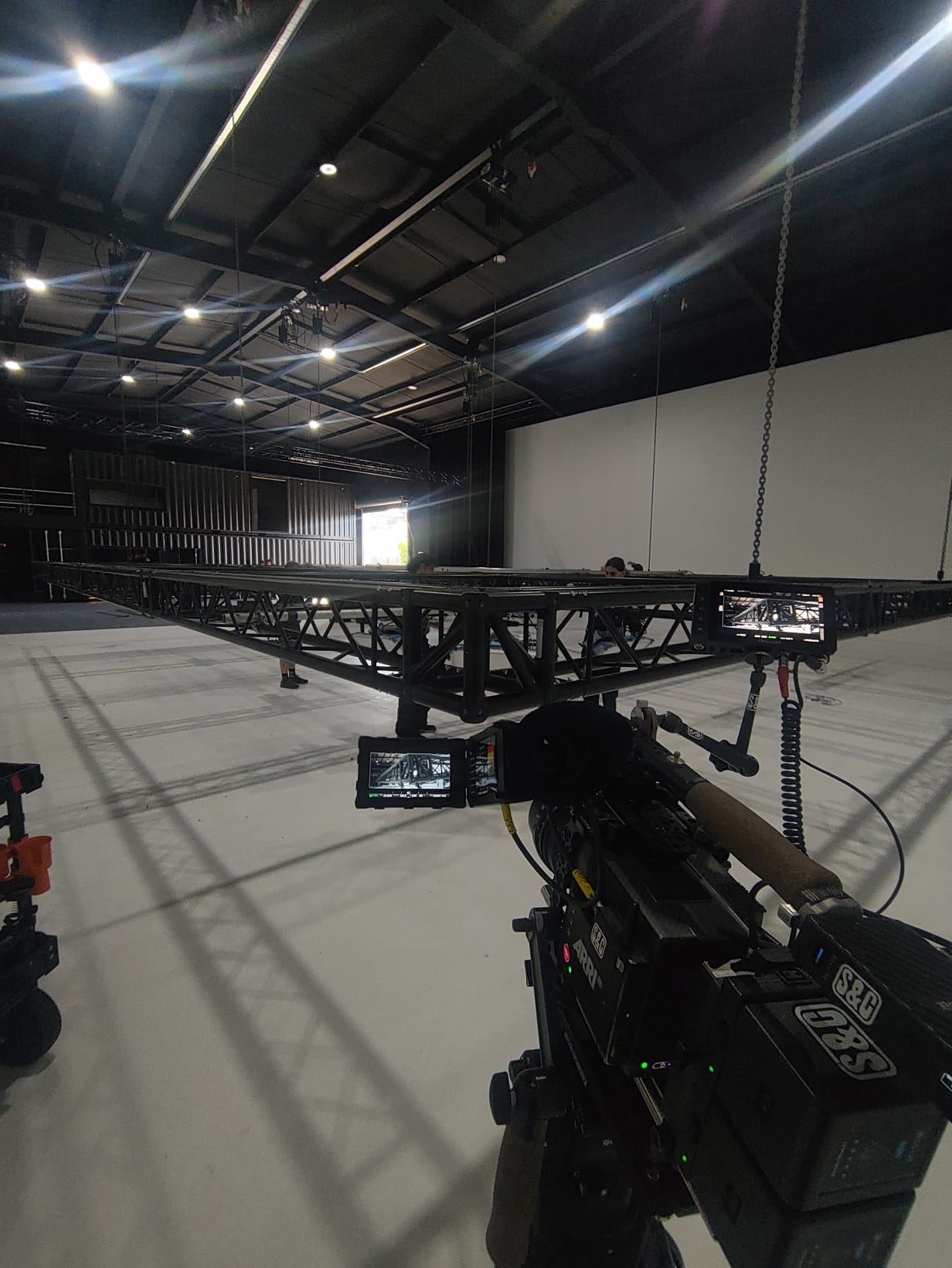 A film soundstage with a long camera-crane truss rigged over a white floor, monitors and an ARRI camera in the foreground.